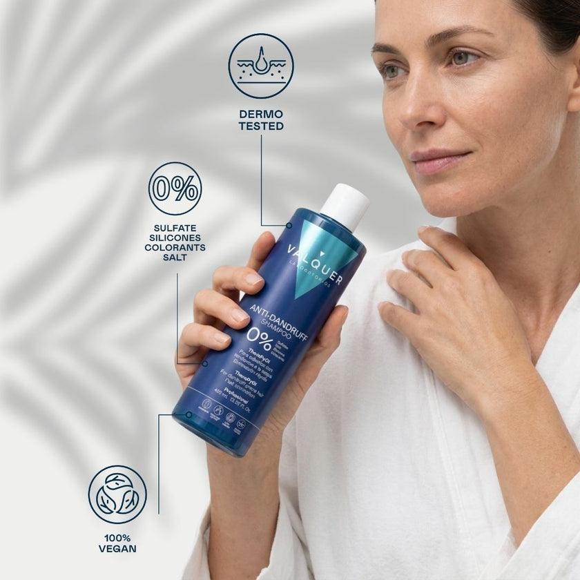 Mujer sosteniendo el champú Anti-Dandruff Valquer, fórmula 0% sulfatos, siliconas, colorantes y sal, 100% vegana y dermatológicamente testada