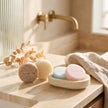 Cosméticos sólidos de Valquer para la higiene facial, corporal y capilar colocados en un baño.