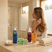 Mujer junto al kit de reparación profunda de Valquer para cabello dañado con mascarilla, protector térmico, bálsamo y champú sólido.