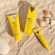 Pack de protección solar facial Valquer con Hydra Sunscreen SPF 50+ y Sérum Solar Invisible con estuche sobre la arena.
