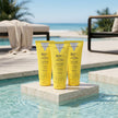 Tres protectores solares faciales Hydra Sunscreen SPF 50+ de Valquer junto a la piscina para proteger e hidratar la piel.